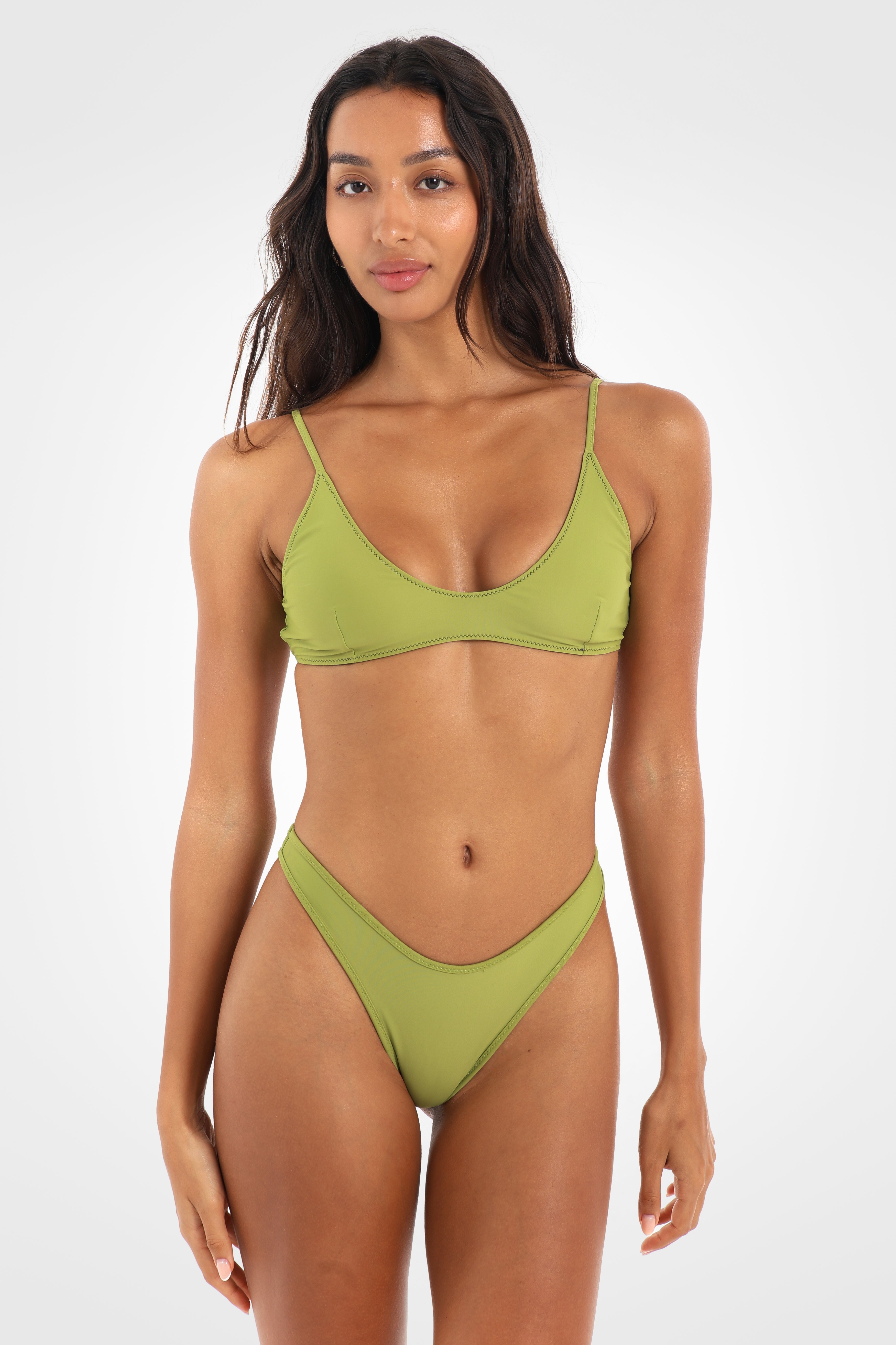 Full front view of the Aruna Reversible Classic High Coverage Bikini Bottoms in pistachio green, showcasing the smooth high-cut silhouette and contrast chocolate brown edging.